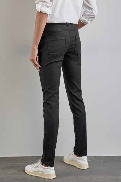 Pantalon noir de Street One, coupe slim, avec poches arrière et porté avec une chemise blanche et des baskets blanches.
