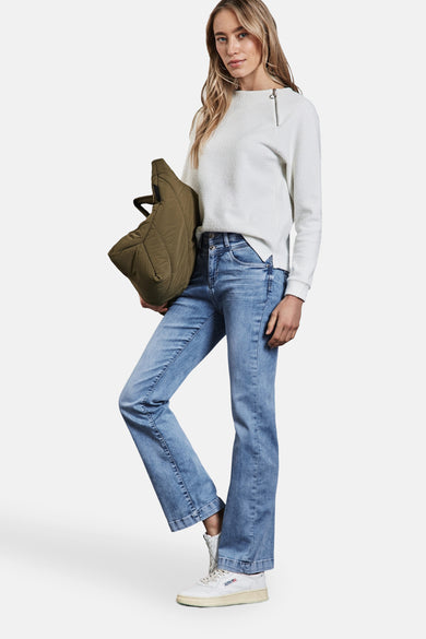 Lichtblauwe bootcut jeans van Street One, gedragen met een witte textuur trui en een olijfgroene gewatteerde tas.