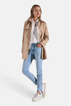 Slim jeans in lichtblauw denim van Street One, gedragen met een wit overhemd en een beige trenchcoat.