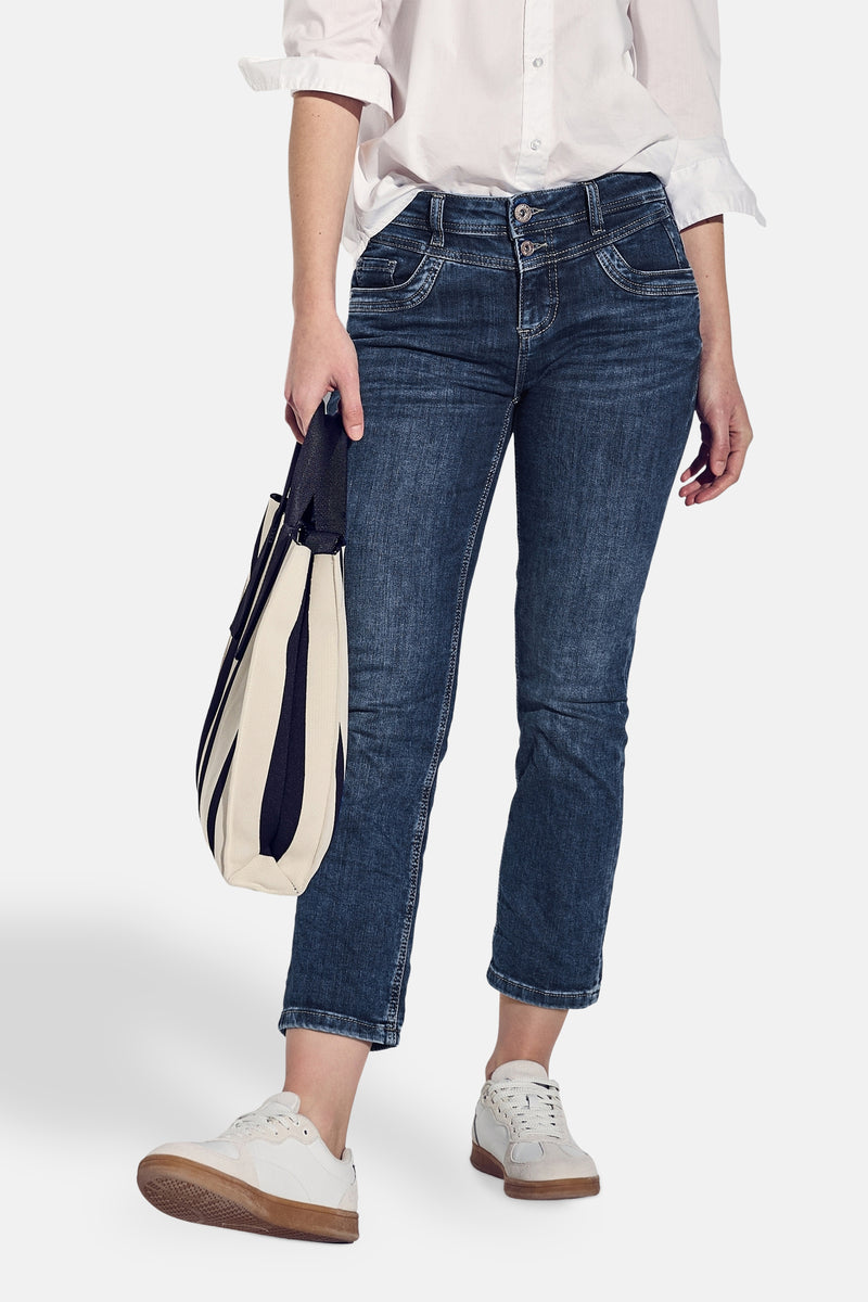 Jean slim en denim bleu foncé de Street One, porté avec une chemise blanche et des chaussures de sport.