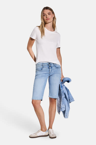 Bermuda en denim bleu clair de STREET ONE, porté avec un t-shirt blanc uni et des chaussures de sport blanches.
