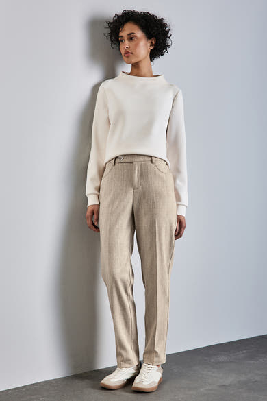 Chino beige by STREET ONE, pantalon en tissu avec poches et bouton, porté avec un pull blanc cassé et des baskets.
