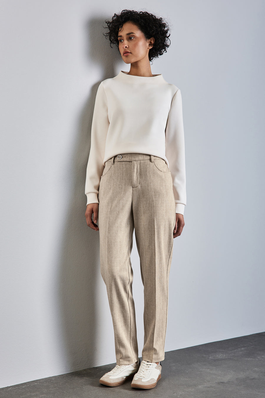 Chino beige by STREET ONE, pantalon en tissu avec poches et bouton, porté avec un pull blanc cassé et des baskets.
