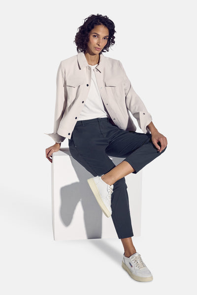 Blauwe chino van STREET ONE gedragen met een wit T-shirt en een beige jasje.
