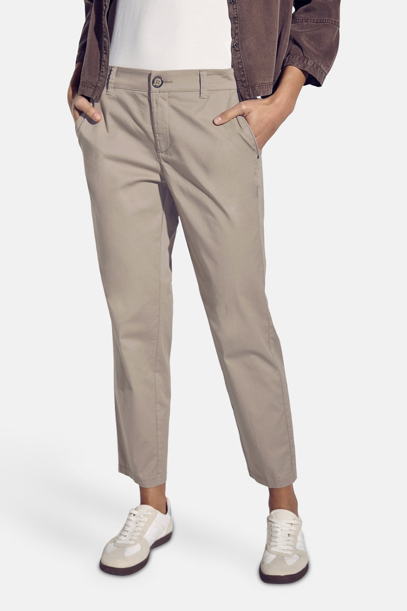 Pantalon chino beige de STREET ONE, avec poches latérales et ourlets chevauchant des chaussures de sport.
