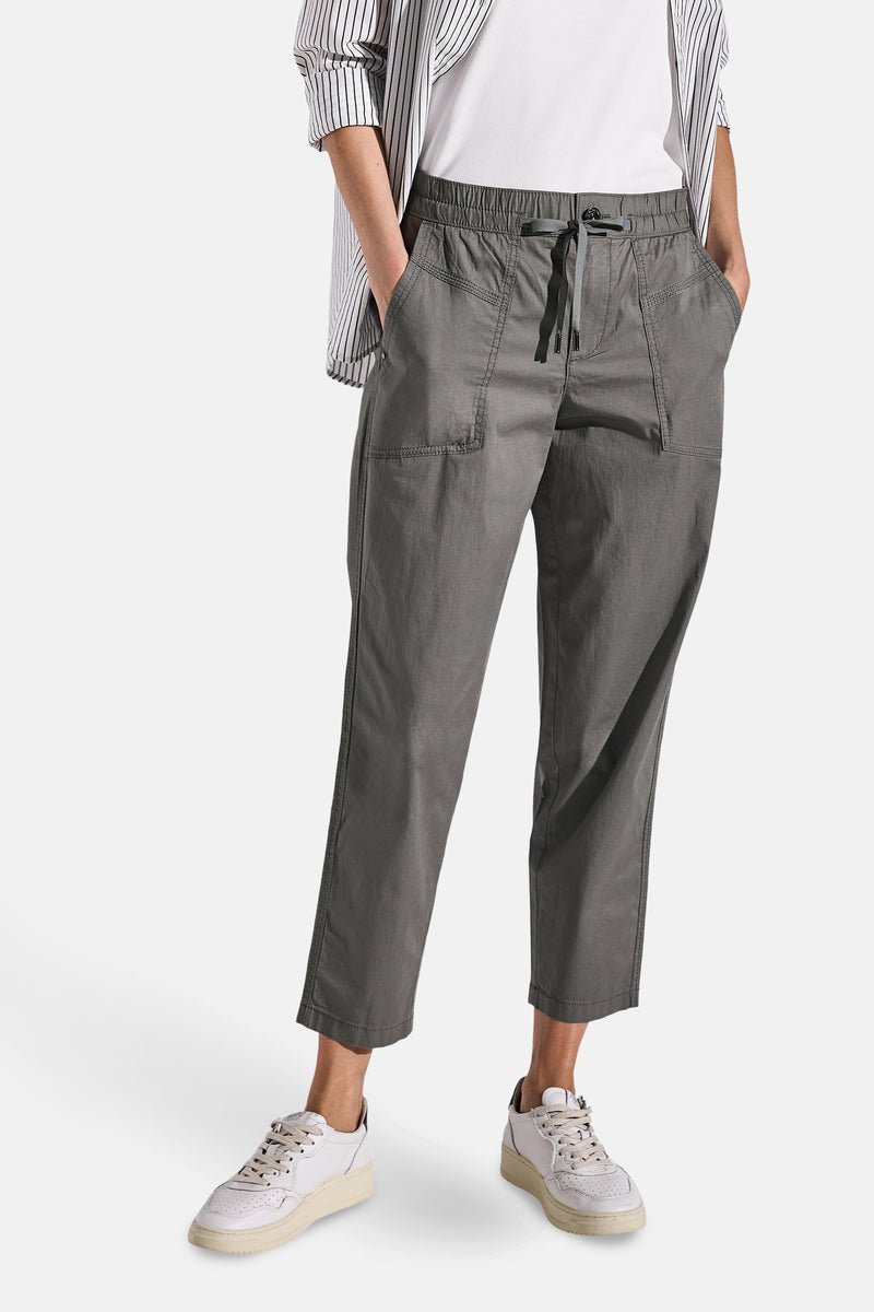 Pantalon cargo gris par Street One, avec cordon de serrage, poches plaquées et portées avec chemise rayée.