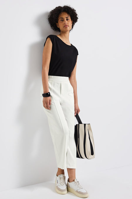 Pantalon blanc de Street One, porté avec un bracelet noir et un sac rayé noir et blanc.