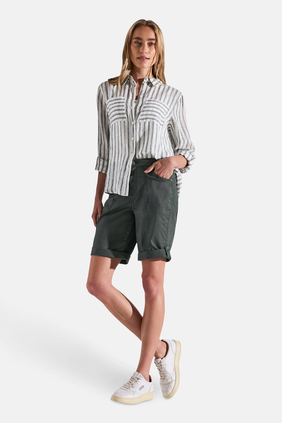 Bermuda kaki de STREET ONE, avec ourlets revers et poches cargo, porté avec une chemise rayée et des baskets blanches.
