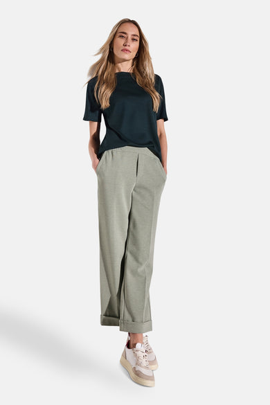 Pantalon vert décontracté de STREET ONE avec une coupe ample et des ourlets retroussés, porté avec un t-shirt noir et des baskets beiges.