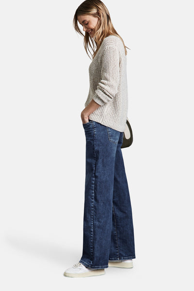 Wijde spijkerbroek in middieblauw denim van STREET ONE, gedragen met een getextureerde trui en witte sneakers.