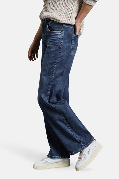 Jean large en denim bleu moyen de Street One, porté avec un pull en tricot et des baskets blanches.
