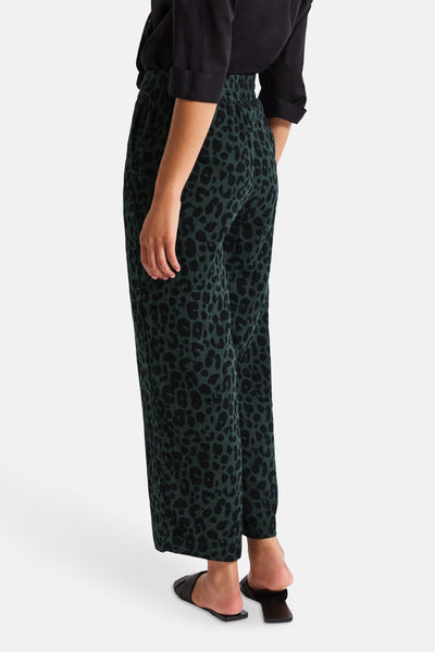 Groene broek met luipaardprint, van Street One, gedragen met een zwart overhemd en sandalen.