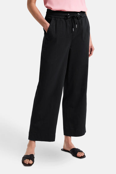 Zwarte wijde broek van Street One, gedragen met een roze T-shirt en zwarte sandalen.