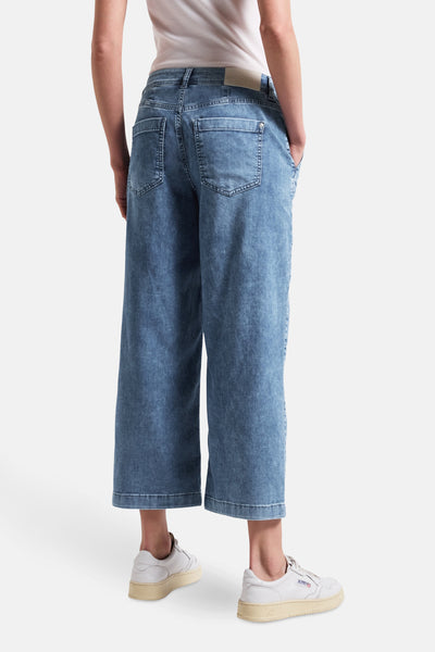 Jean large en denim bleu moyen de Street One, porté avec un t-shirt blanc et des baskets blanches.
