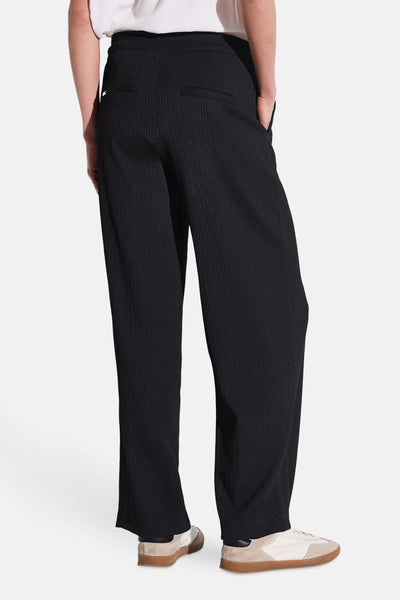 Pantalon noir de STREET ONE, coupe ample, texture côtelée, porté avec des chaussures de sport.