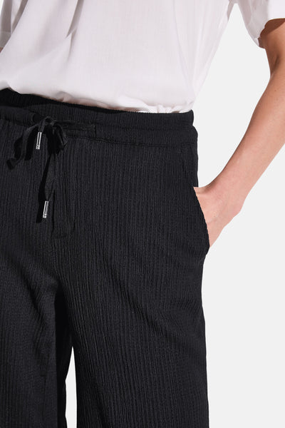 Pantalon noir texturé de STREET ONE, avec cordon de serrage et poche, porté avec un t-shirt blanc.