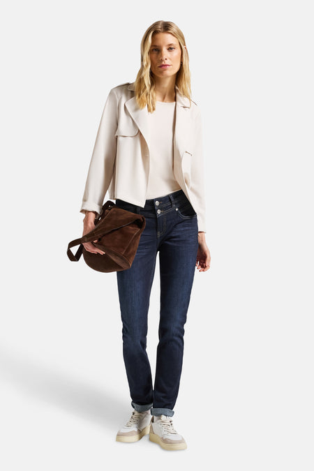 Jean slim bleu denim moyen de STREET ONE, porté avec un haut crème et une veste beige et un sac à main en cuir marron.
