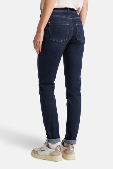 Jean slim bleu denim par STREET ONE, avec revers et chaussures de sport beiges.
