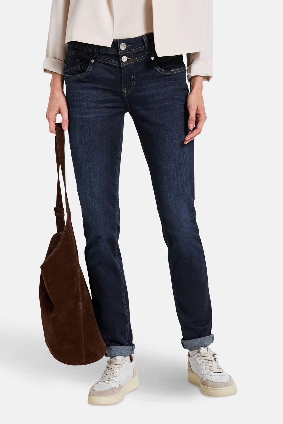 Jean slim en denim bleu moyen de STREET ONE, porté avec un sac marron et des baskets blanches.