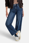 Jean large en denim bleu moyen de Street One, porté avec une veste marron et des baskets blanches.