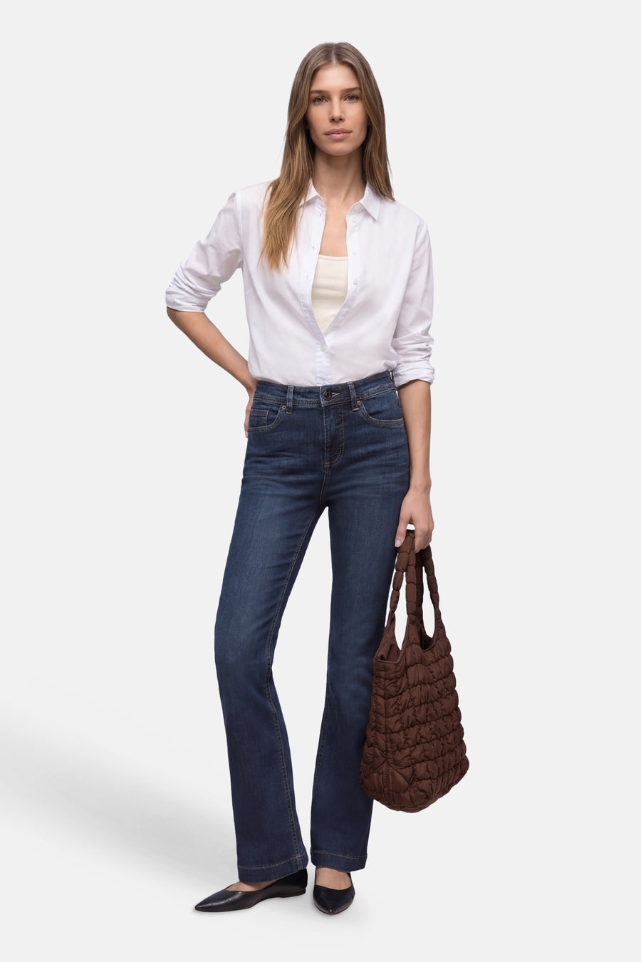 Jean bootcut en denim bleu foncé de STREET ONE, porté avec une chemise blanche et un sac matelassé marron.