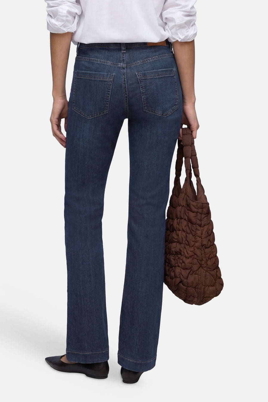 Jean bootcut en denim bleu foncé de STREET ONE, vu de dos, avec une chemise blanche et un sac matelassé marron.