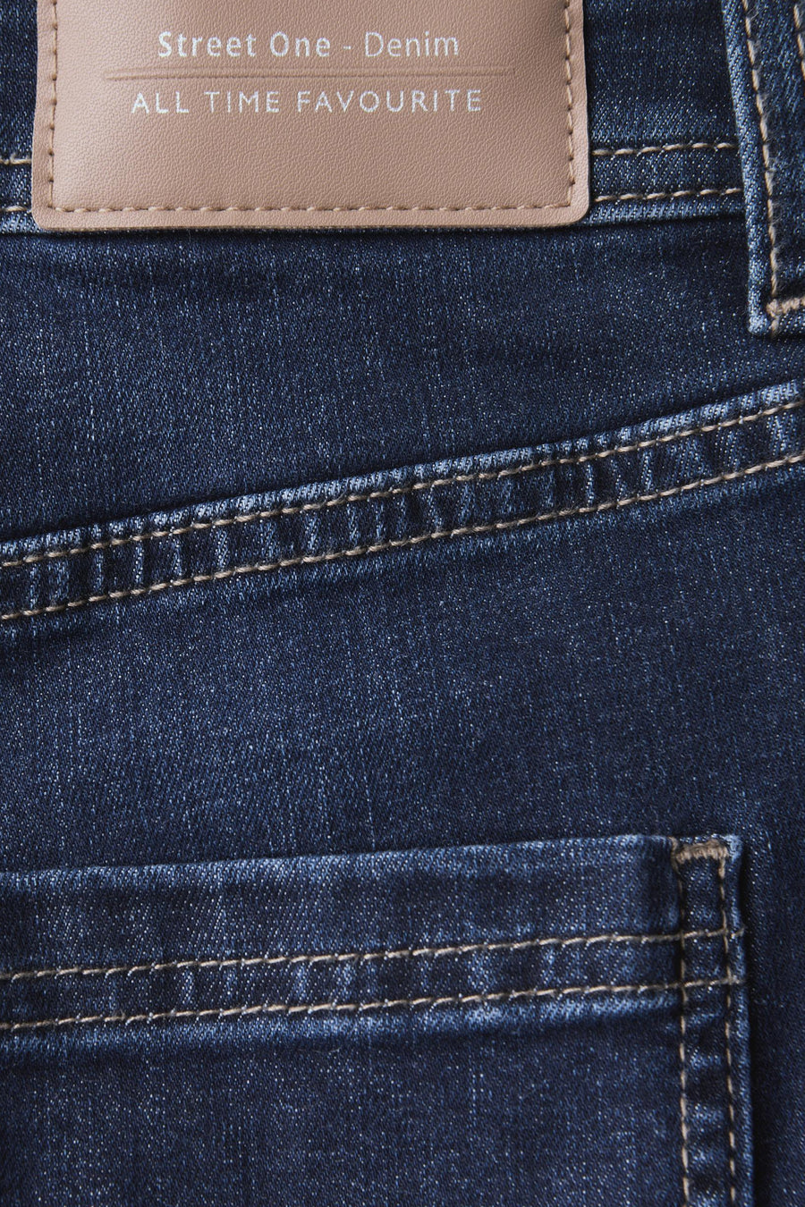 Jean bootcut en denim bleu foncé de STREET ONE, gros plan de la poche arrière avec surpiqûres marron clair et étiquette en cuir beige.