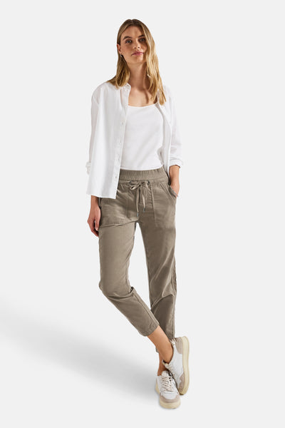 Pantalon coloré brun de Street One, porté avec un t-shirt blanc et une chemise blanche ouverte.
