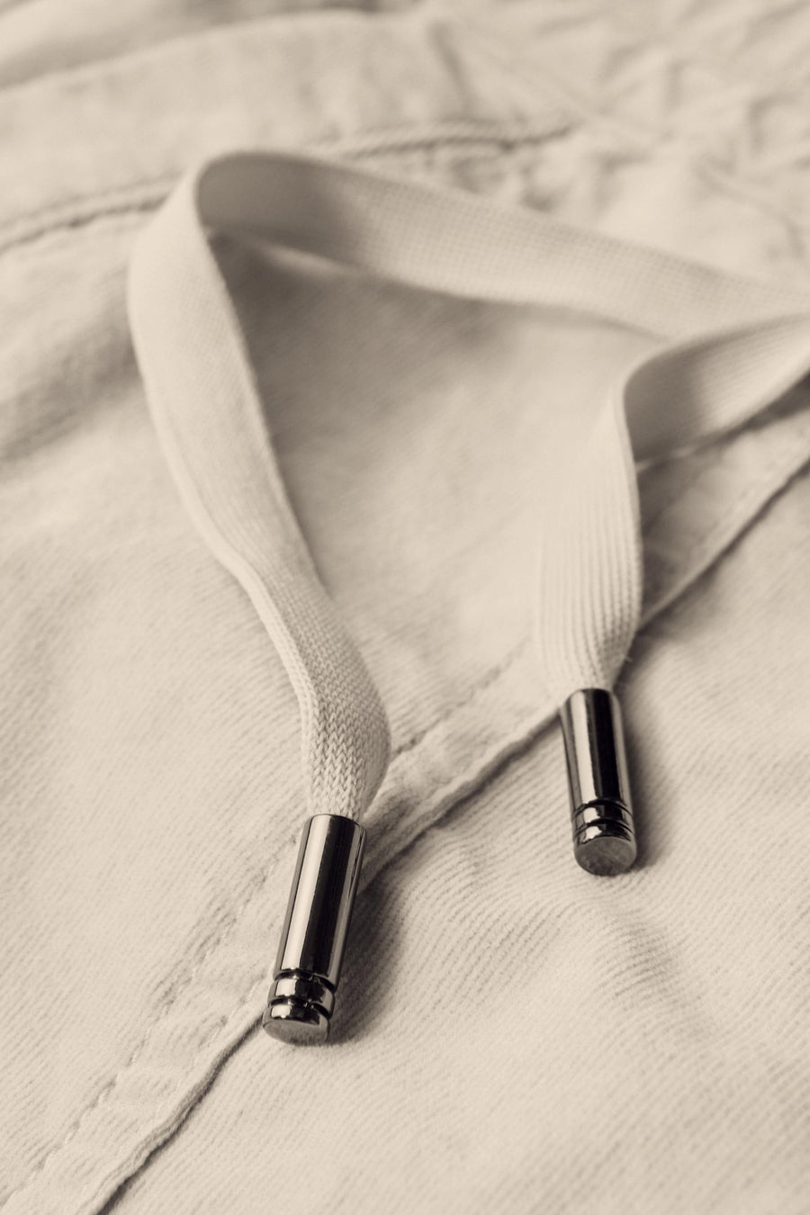 Pantalon coloré écru par Street One, avec cordon de serrage et extrémités métalliques brillantes, en gros plan.
