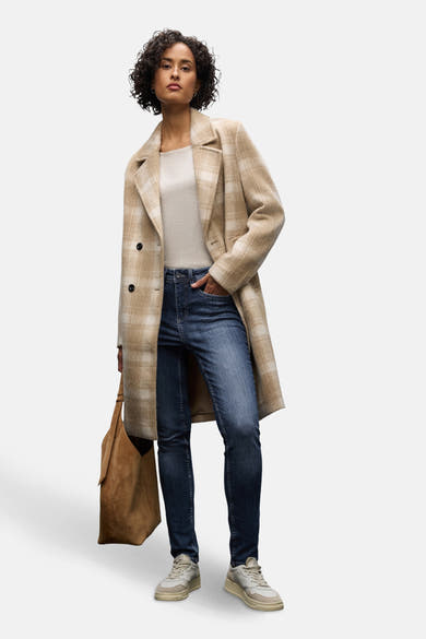 Slim jeans in donkerblauw denim van Street One, gedragen met een geruite jas en een suède tas.