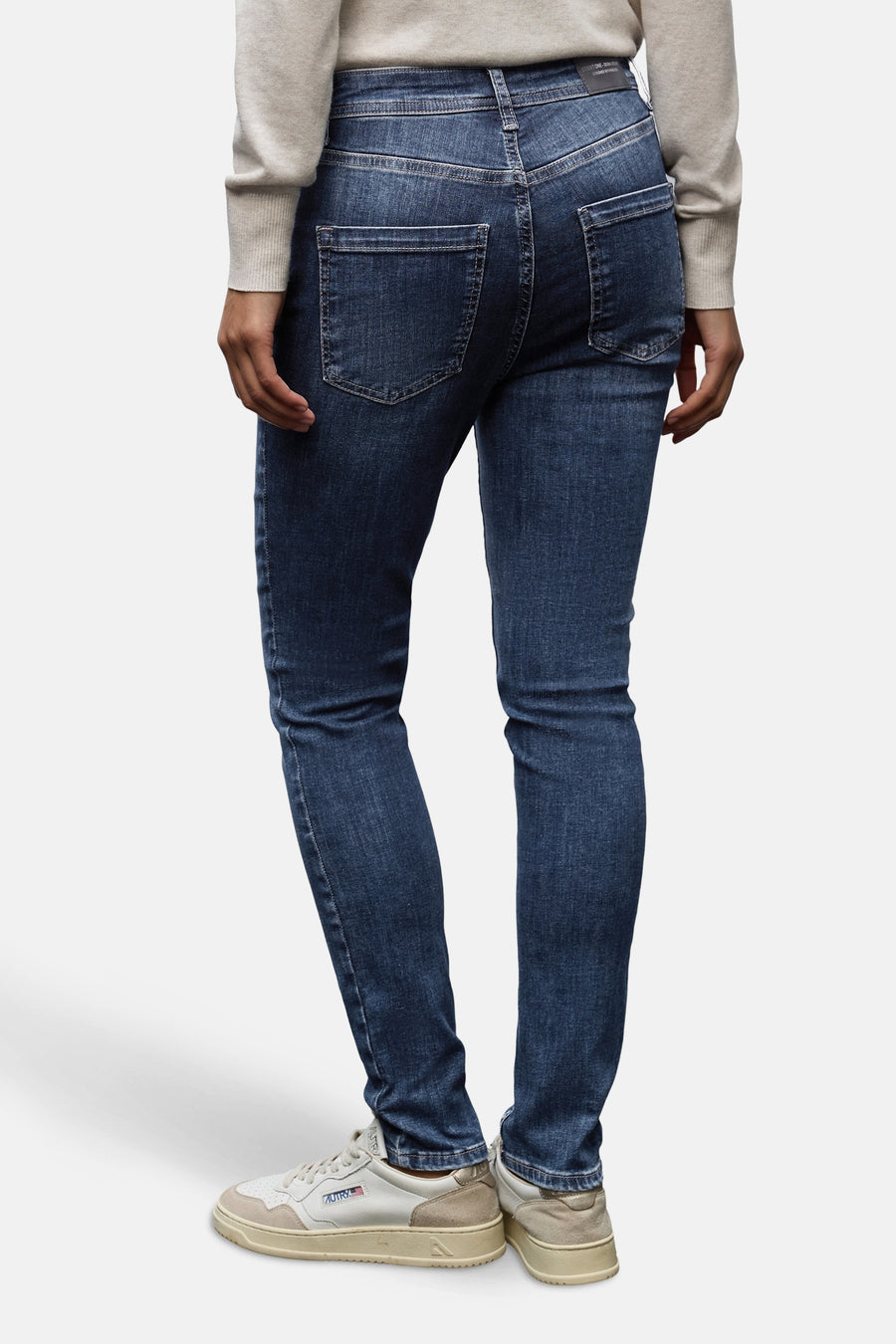 Slim jeans in donkerblauw denim van STREET ONE, gedragen met een beige trui en witte sneakers.