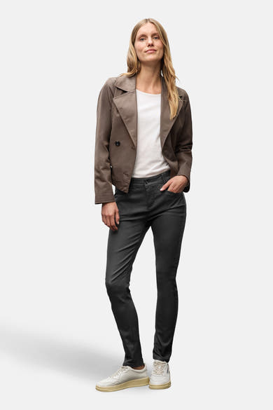 Zwarte broek van Street One gedragen met een bruin jasje en sneakers, met één hand in de zak.