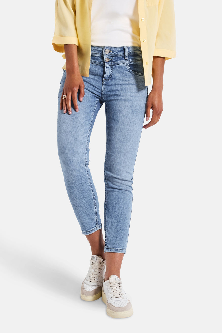 Slim jeans in lichtblauw denim van Street One, gedragen met een gele blouse en beige sneakers.
