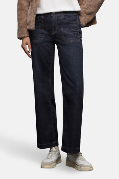 Jean large en denim bleu foncé de STREET ONE, porté avec un manteau en fausse fourrure marron et des baskets blanches.

