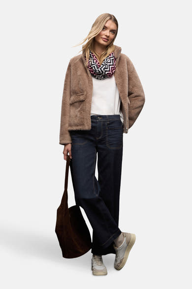 Jean large en denim bleu foncé de STREET ONE, porté avec un manteau texturé et un foulard à motifs.
