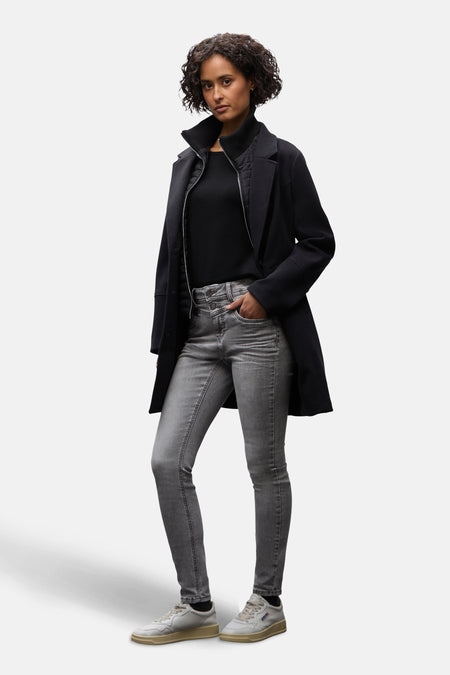 Jean slim en denim gris moyen de STREET ONE, porté avec un manteau noir et des baskets blanches.
