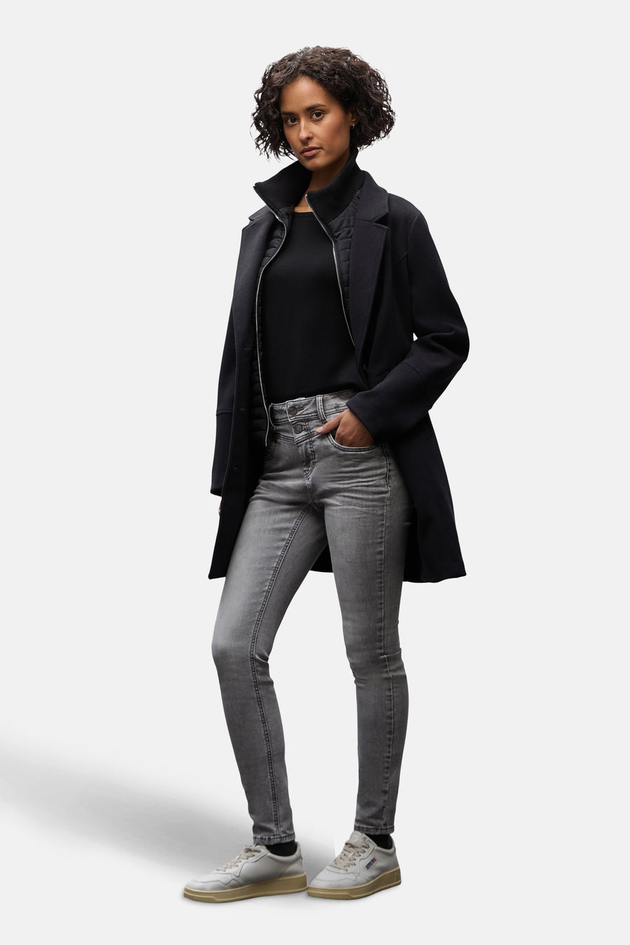 Jean slim en denim gris moyen de STREET ONE, porté avec un manteau noir et des baskets blanches.
