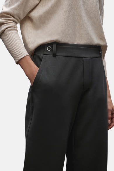 Zwarte pantalon van STREET ONE, met een persoon die een beige trui draagt en de handen in de zakken heeft.