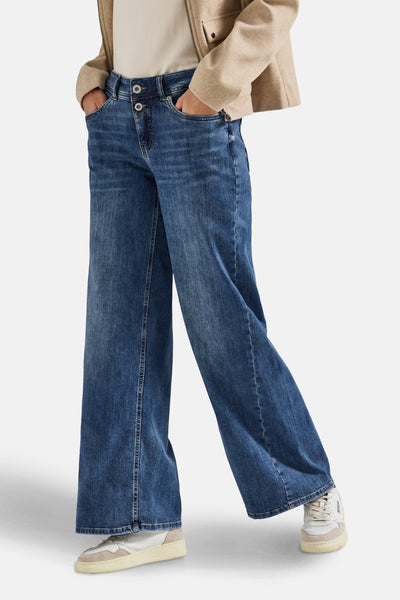 Jean large en denim bleu moyen de STREET ONE, avec poches et ourlets bruts, porté avec une veste beige.
