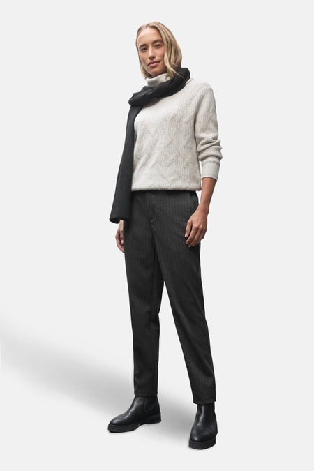 Pantalon de costume noir par Street One, avec une texture fine et des bottes noires.
