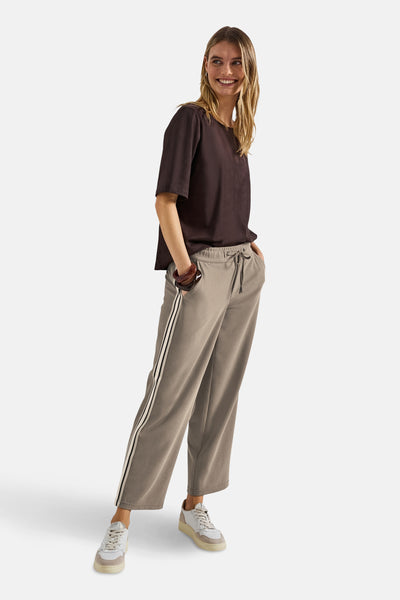 Bruine broek, STREET ONE, met witte zijstrepen, gedragen met een bruin T-shirt en witte sneakers.