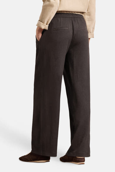 Pantalon brun de STREET ONE, coupe large, taille élastiquée et tissu texturé avec poches passepoilées, porté avec une chemise beige et des baskets marron.