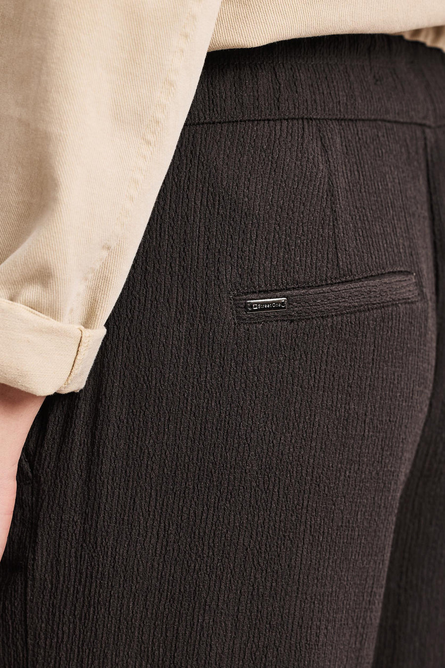 Pantalon brun de STREET ONE en tissu texturé, avec étiquette métallique sur une fausse poche et chemise beige.