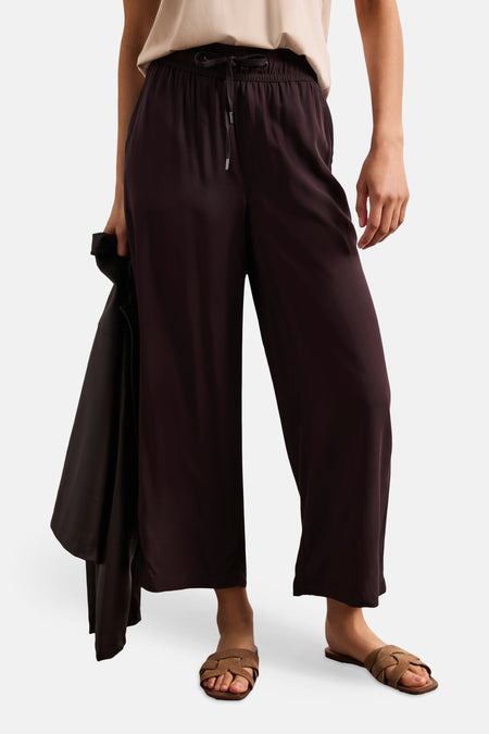Pantalon brun fluide de STREET ONE avec taille élastiquée et cordon, porté avec un haut clair et des sandales tressées.