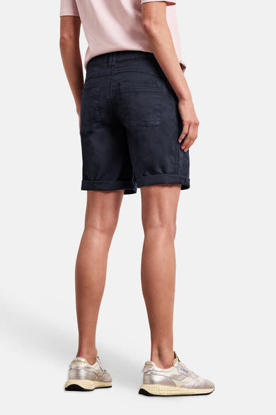 Bermuda bleu de STREET ONE coupe décontractée avec revers, porté de dos avec un t-shirt rose et des baskets.