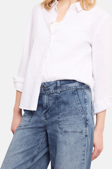 Jean large en denim bleu moyen de STREET ONE, à fines rayures verticales, taille mi-haute, bouton métallique et poches apparents, porté avec une chemise blanche.