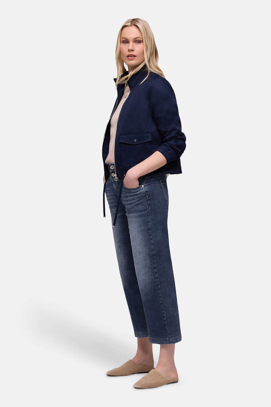Jean large en denim bleu moyen de Street One, porté avec une veste bleu marine et des mules beiges.
