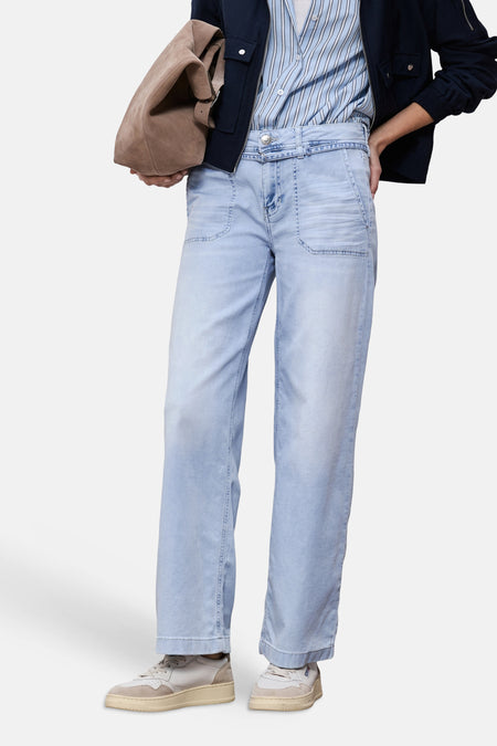 Wijde spijkerbroek in lichtblauw denim van STREET ONE, gedragen met een gestreept overhemd, een marineblauw jack en lichte sneakers.