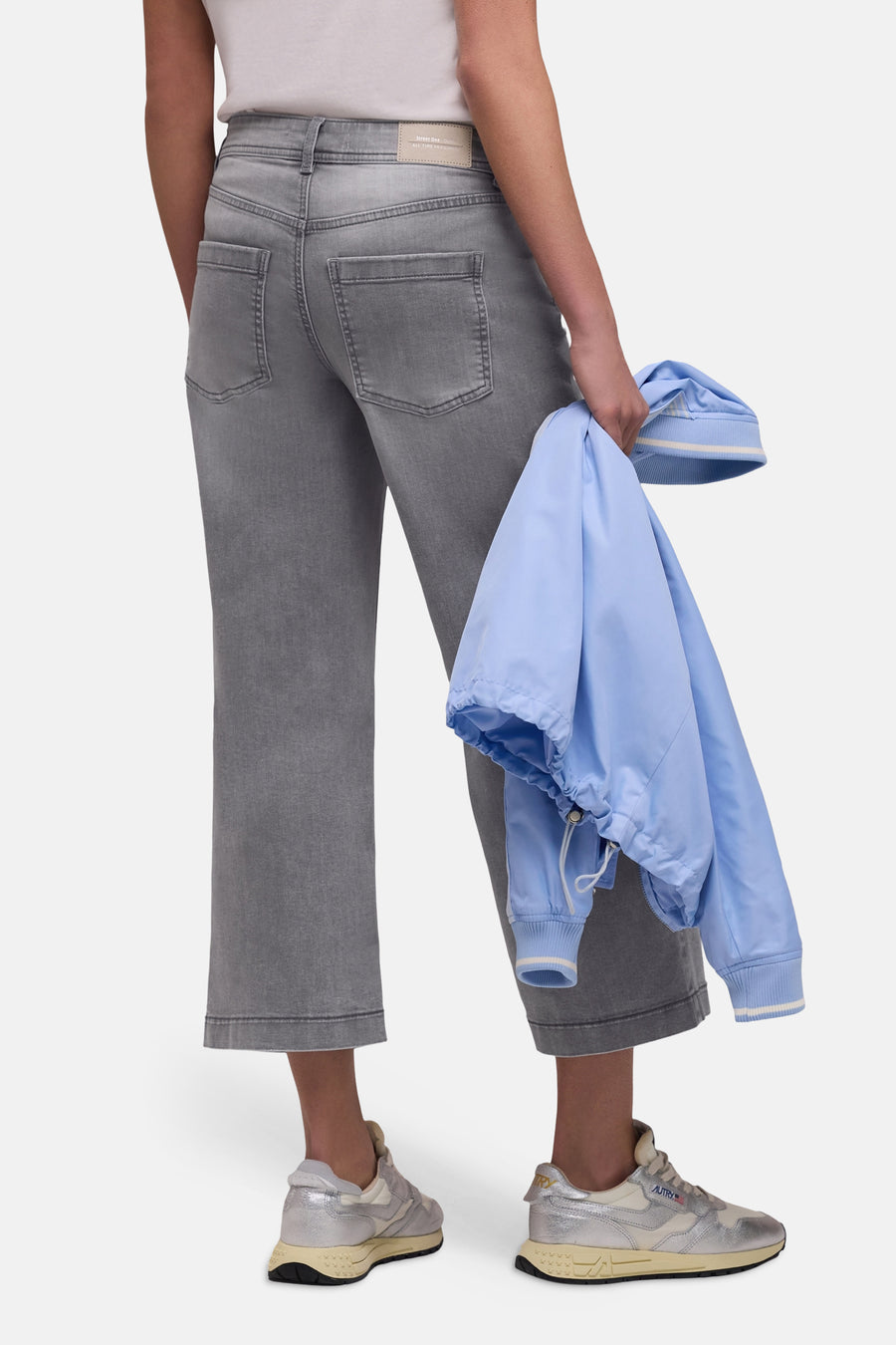 Jean large en denim gris de STREET ONE, porté avec des chaussures de sport argentées et veste bleu clair à rayures.