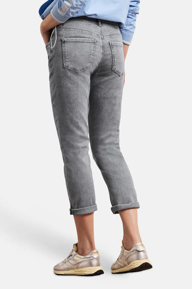 Grijze denim slim fit jeans van STREET ONE, van achteren gezien, opgerold bij de enkels, gedragen met sneakers en een blauw overhemd.
